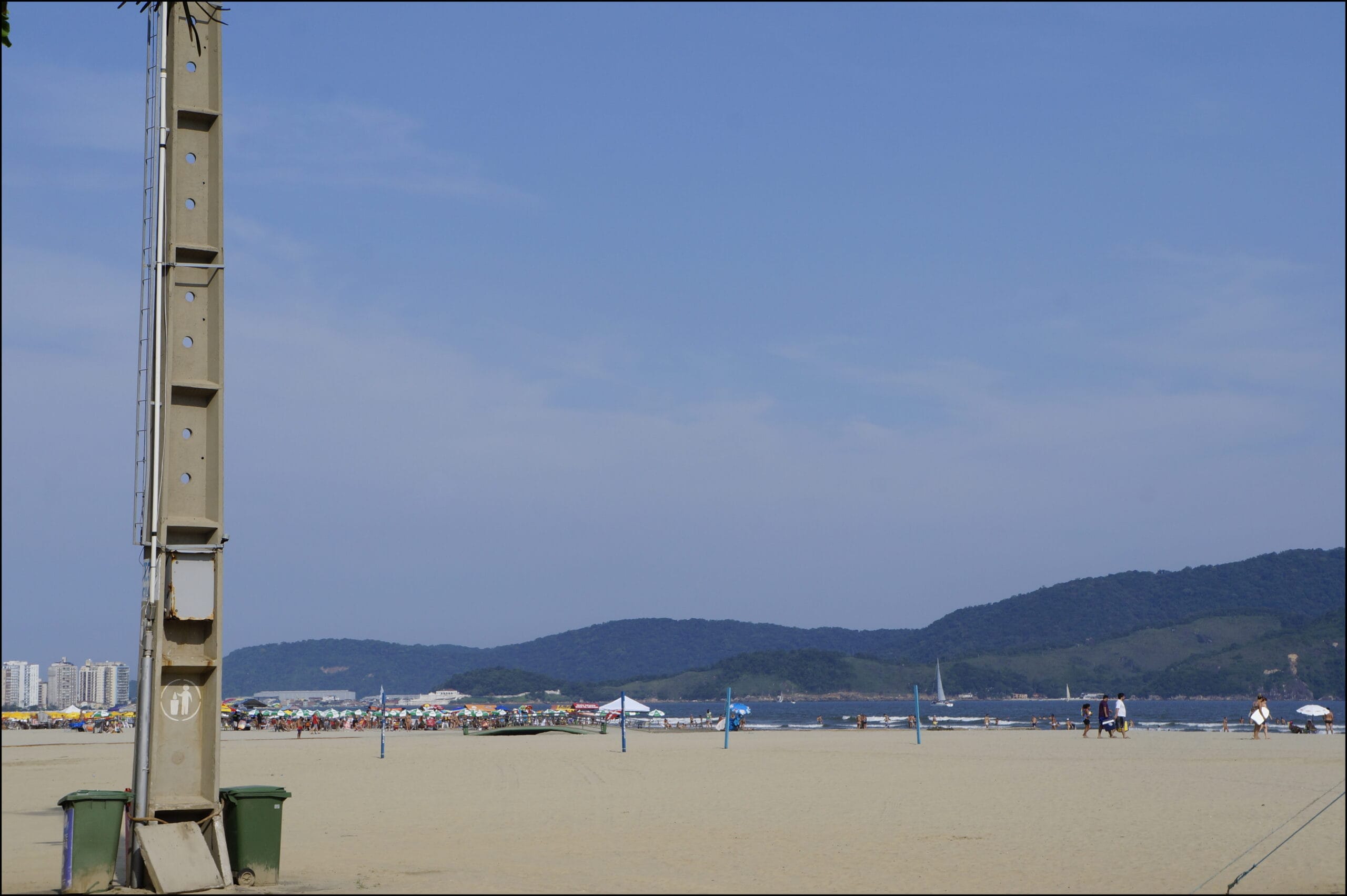 Vista da Praia do Gonzaga em Santos, com faixa de areia, jardins frontais e prédios do bairro ao fundo