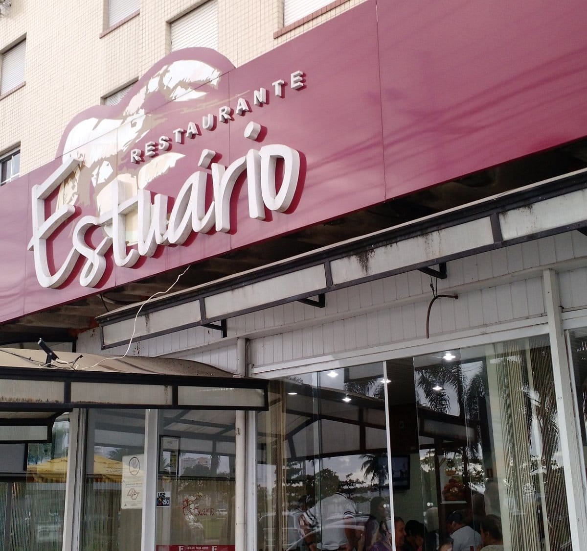 Fachada do Restaurante Estuário com letreiro estilizado em rosa na Av. Bartolomeu de Gusmão