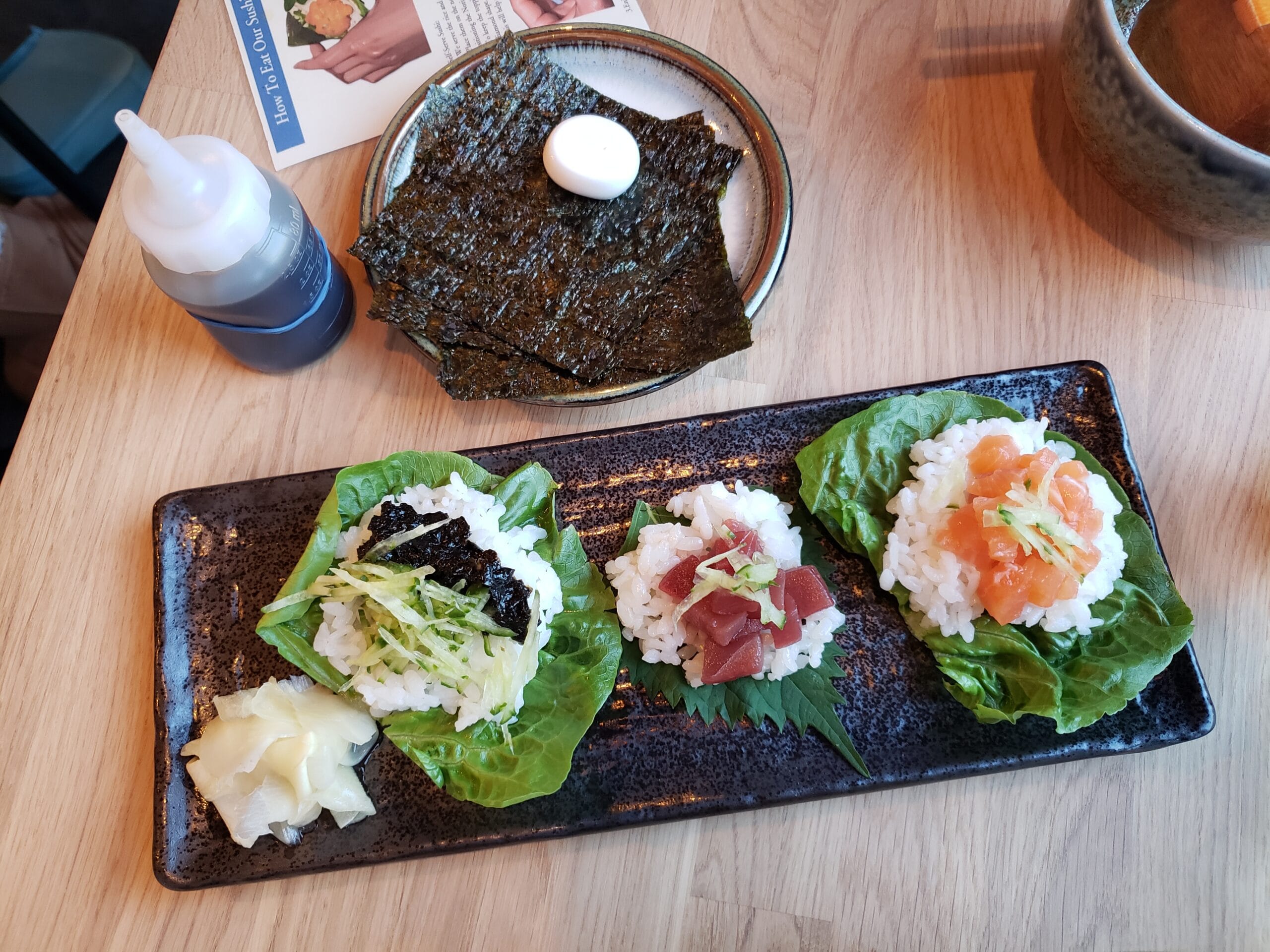 Trio de temakis de salmão, atum e pepino servidos em suporte de madeira