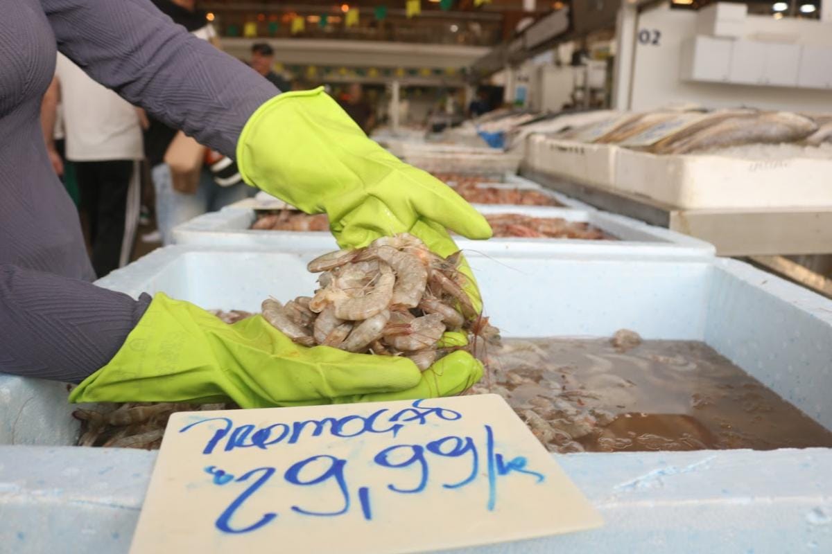 Feirante com luvas segura camarões frescos nos boxes do Mercado de Peixes de Santos, na Ponta da Praia