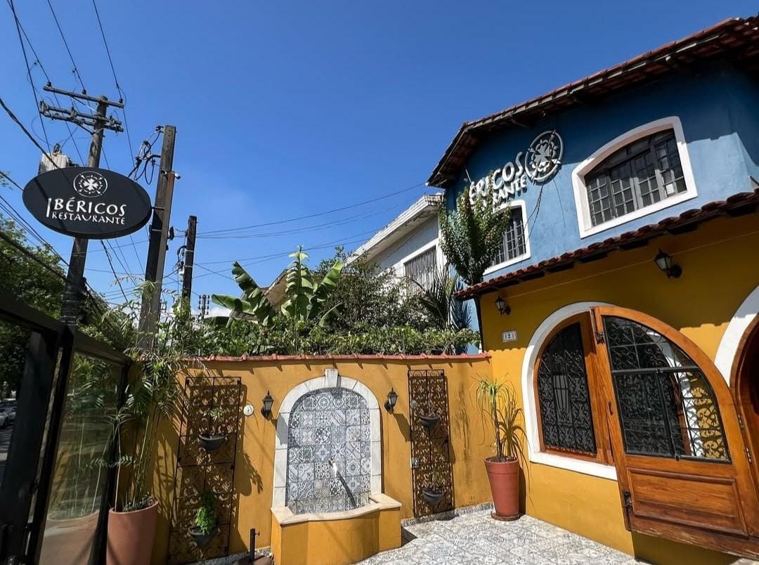 Fachada azul e amarela do restaurante Ibericos Gastronomia, na Vila Mathias, em Santos