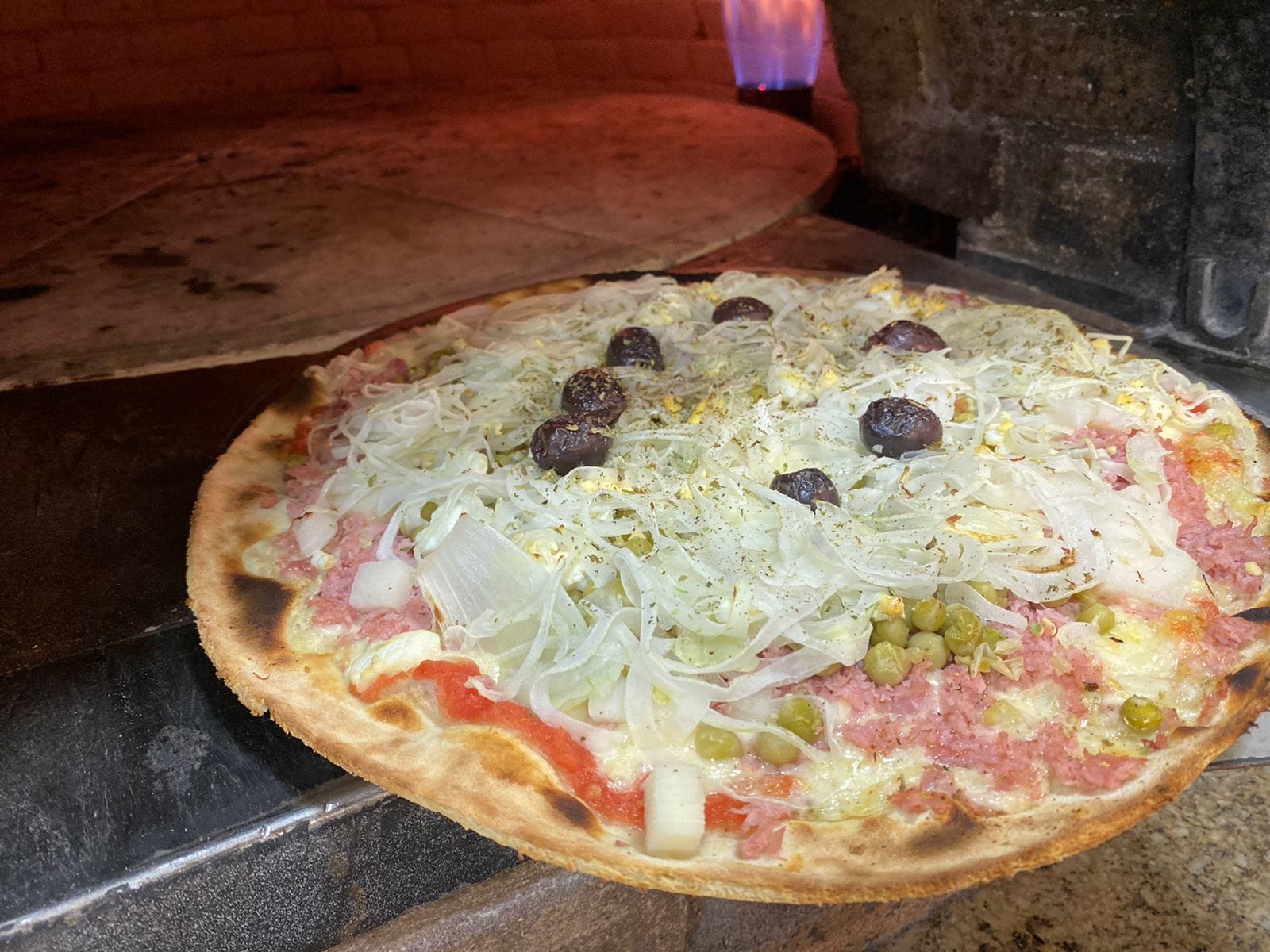 Pizza recem-assada saindo do forno a lenha da Kokimbos, no Boqueirao, em Santos